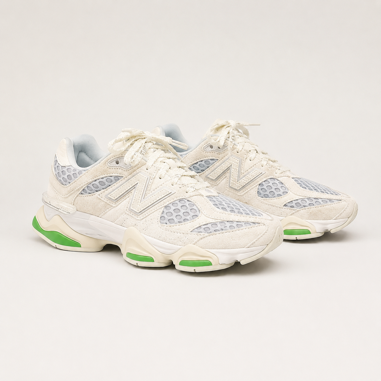 New Balance 9060 sneakers in sea salt cream suede with green sole pods, angled pair view