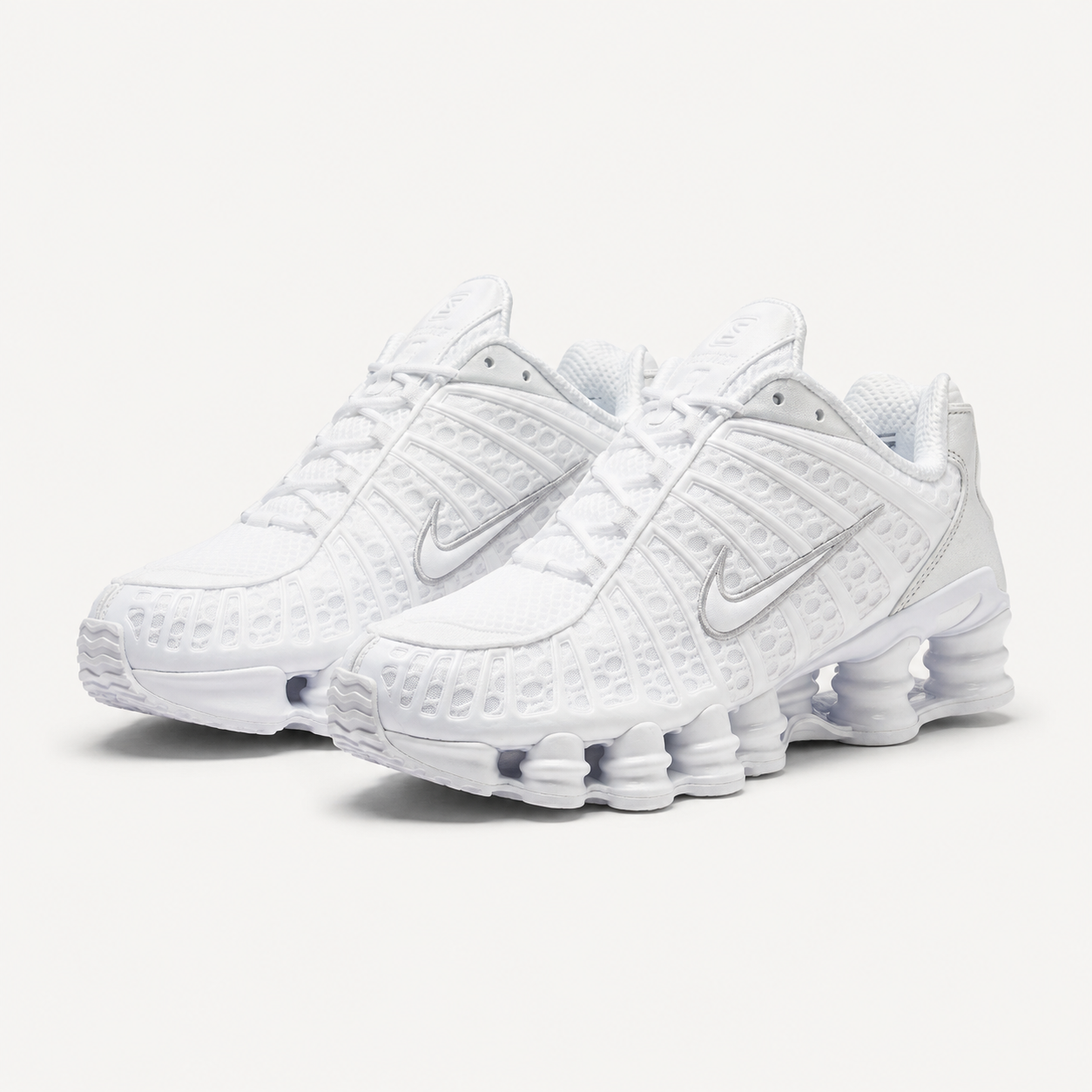 Nike Shox TL sneakers in triple white with metallic silver Swoosh, angled pair view